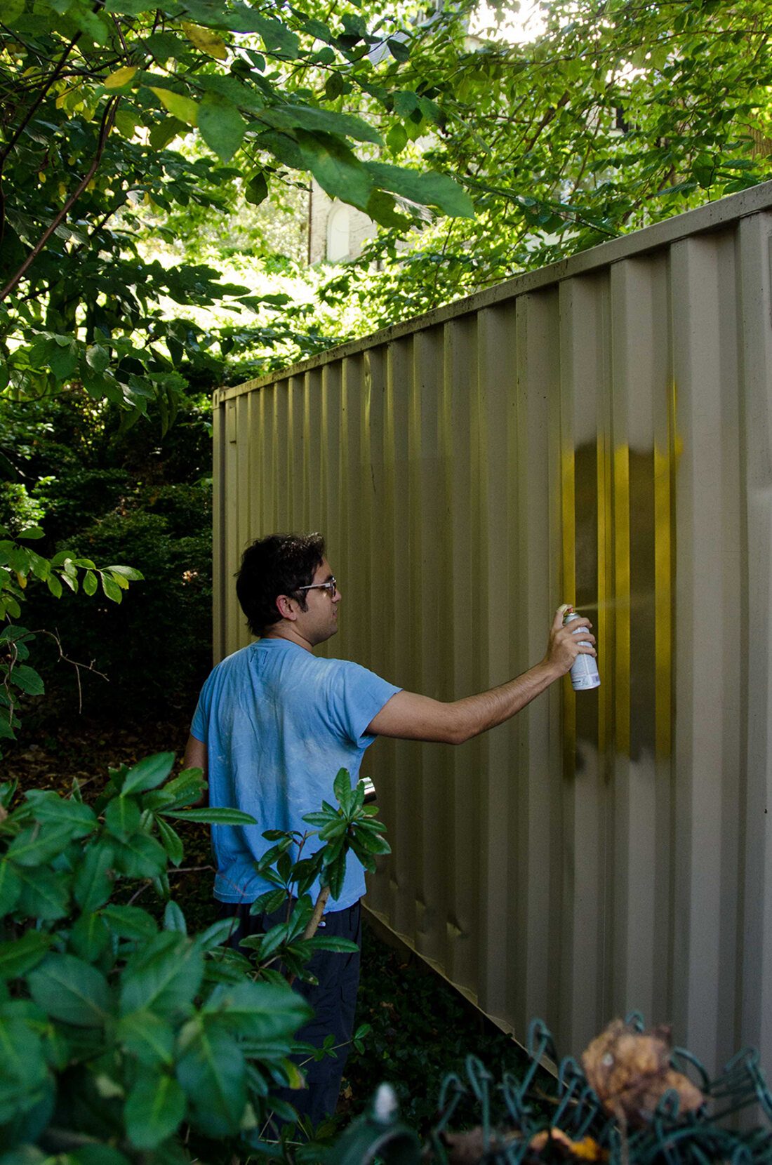 Painting a shipping container gold by hand, in a suburban backyard