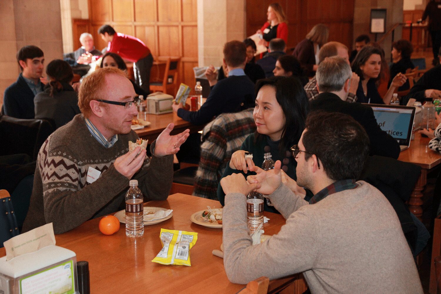Attendees in conversation over lunch in a stone hall