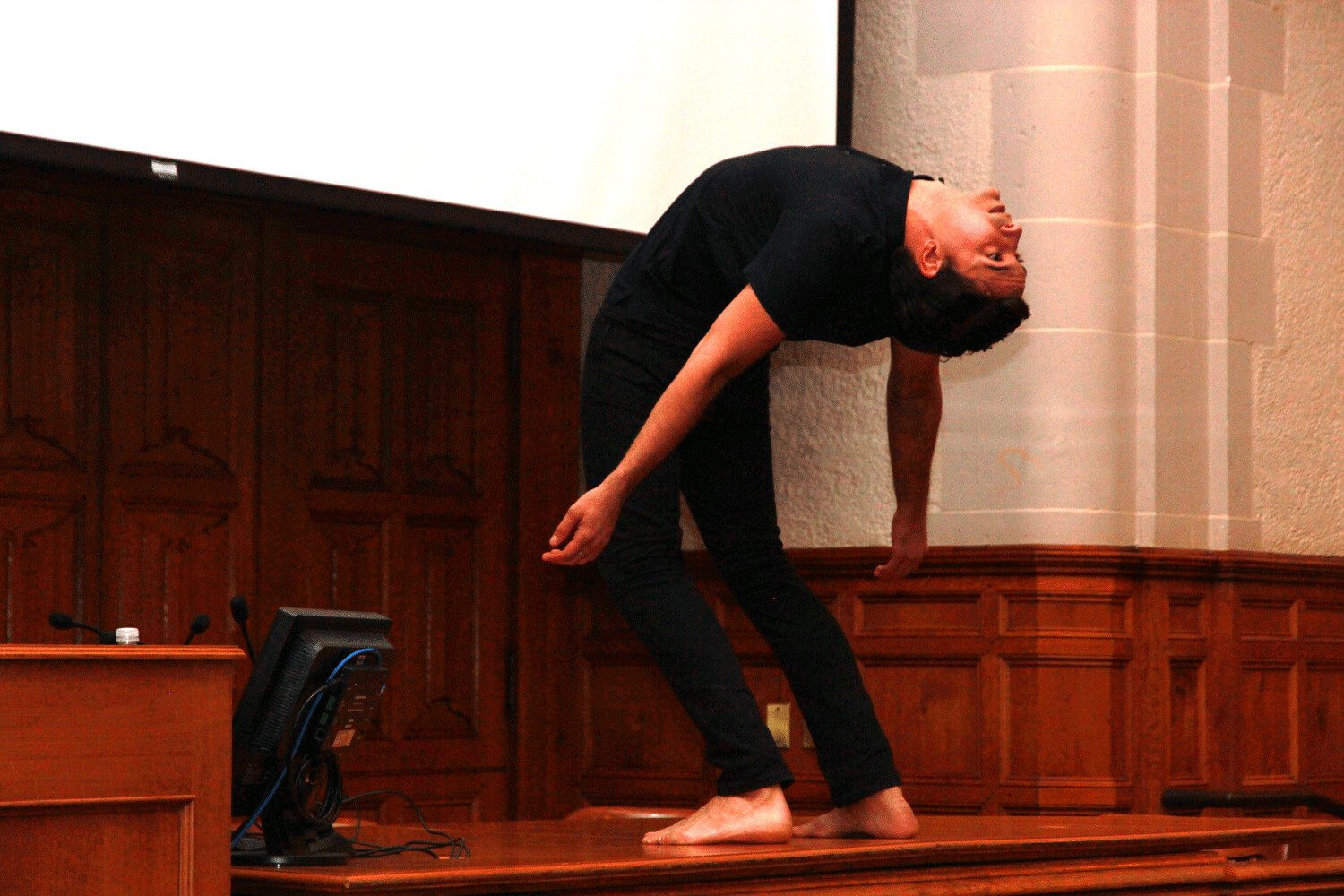 Jonah Bokaer dancing barefoot atop the lecture bench