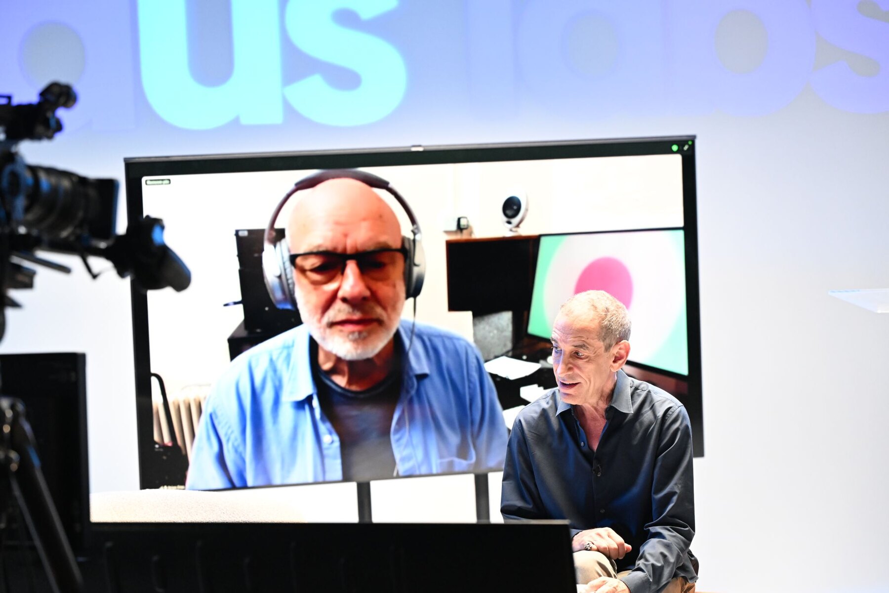An AfterNow conversation being filmed — a remote participant on screen, the host responding on set